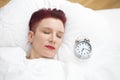 Woman lying in bed with alarm clock on pillow Royalty Free Stock Photo