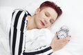 Woman lying in bed with alarm clock on pillow Royalty Free Stock Photo