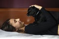 Woman lying in bed with a black dog Royalty Free Stock Photo