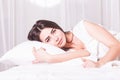 Woman is lying in bed with her head on the pillow and hands under it. Royalty Free Stock Photo