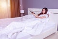 Woman lying on a bed with remote control and watching television Royalty Free Stock Photo