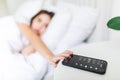 Young Woman Lying on Bed Snoozing Alarm On Mobile Phone