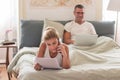 Woman lying on bed, talking on phone and holding paper in hands