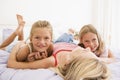 Woman lying in bed with two young girls smiling Royalty Free Stock Photo