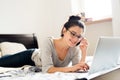 Woman lying on bed, working on laptop, calling. Home office. Royalty Free Stock Photo