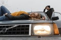 Woman lying on the car hood and man standing near the car door