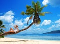 Woman lying on the coconut palm tree. Tropical beach in La Digue Island, Seychelles. Royalty Free Stock Photo