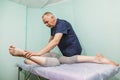 Woman lying on a couch and a chiropractor works with her legs - Physiotherapist stretching leg of patient. Physical therapy