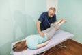 Woman lying on a couch and a chiropractor works with her legs - Physiotherapist stretching leg of patient. Physical therapy