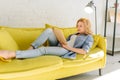 Woman lying on cozy yellow couch and reading book Royalty Free Stock Photo