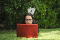 Woman lying down on the grass of a park working on her laptop with her feet up. Royalty Free Stock Photo