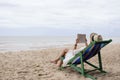 A woman lying down and reading book on the beach chair with feeling relaxed Royalty Free Stock Photo