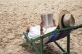 Woman lying down and reading book on the beach chair with feeling relaxed Royalty Free Stock Photo