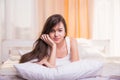 A woman lying at the end of the bed underneath the quilt and smiling, Royalty Free Stock Photo