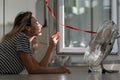 Woman lying on floor in front of electric fan in hot summer day, enjoying cooling wind, fresh air Royalty Free Stock Photo