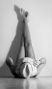 Woman lying on the floor with the legs up on the wall holding her hat