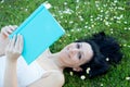 Woman lying on a flowered meadow reading a book Royalty Free Stock Photo