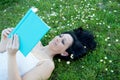 Woman lying on a flowered meadow reading a book Royalty Free Stock Photo