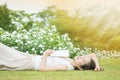 Asian woman lying grass field after she tired for reading a book in the afternoon