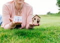 Woman lying on the grass holding toy houses on her palms. Royalty Free Stock Photo