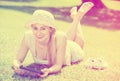 Woman lying on green grass in park and holding mobile phone in h Royalty Free Stock Photo