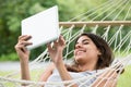 Woman Lying On Hammock Looking At Digital Tablet Royalty Free Stock Photo