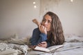 Woman lying on her bed thinking about what to write in her journal