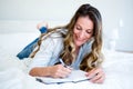 woman lying on her bed writing in a book Royalty Free Stock Photo