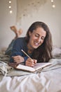 Woman lying on her bed writing in her notebook