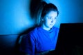 Woman lying with her laptop in night in the bedroom in blue light at screen