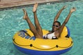 Woman lying on inflatable raft in swimming pool with arms and legs raised portrait.