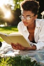 Woman lying outdoors in park on a grass and reading a book Royalty Free Stock Photo