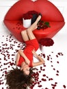 Woman lying on red lips sofa couch roses bouquet flowers petals Royalty Free Stock Photo