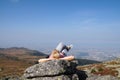 A woman lying resting on the top of a mountain, at the foot of which there is a large metropolis