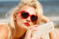 Woman lying on sandy beach using cell phone Royalty Free Stock Photo