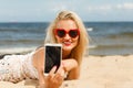 Woman lying on sandy beach using cell phone Royalty Free Stock Photo