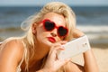 Woman lying on sandy beach using cell phone Royalty Free Stock Photo