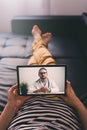 Woman lying on a sofa and talking with a doctor online using digital tablet. Telemedicine concept. Royalty Free Stock Photo