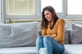 Woman lying on sofa looking sick in the living room. Beautiful young woman lying on bed and holding hands on her stomach. Woman Royalty Free Stock Photo