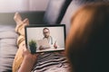 Woman lying on a sofa and talking with a doctor online using digital tablet. Telemedicine concept. Royalty Free Stock Photo