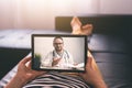 Woman lying on a sofa and talking with a doctor online using digital tablet. Telemedicine concept. Royalty Free Stock Photo