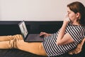 Woman lying on a sofa and talking with a doctor online using laptop. Telemedicine concept. Royalty Free Stock Photo