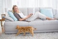 Woman lying on sofa using her laptop smiling at camera Royalty Free Stock Photo