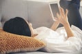 Woman lying on the sofa using mobile phone to work at home. Asian Female holding phone and touch screen via tablet. Technology Royalty Free Stock Photo