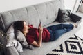 Woman lying on the sofa and using smartphone at home Royalty Free Stock Photo