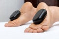 Woman lying on stomach, female masseuse doing legs and feet massage with hot stones Royalty Free Stock Photo