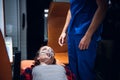 A woman lying on a stretcher with an oxigen mask on and looking at the paramedic in a blue uniform Royalty Free Stock Photo