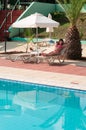 Woman lying on sun lounge near swimming pool at resort, blue calm water Royalty Free Stock Photo