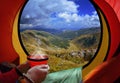 Woman lying in a tent with coffee ,view of mountains and sky Royalty Free Stock Photo