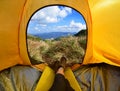 Woman lying in tent with a view of mountain and sky Royalty Free Stock Photo